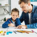 Handsome Young Father Drawing With Son At Home
