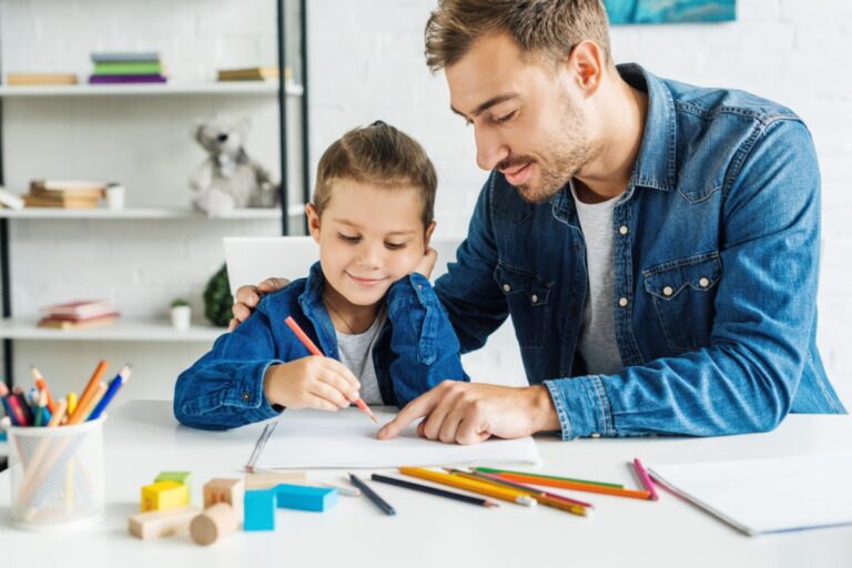 Handsome Young Father Drawing With Son At Home
