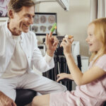 Doctor Playing With Little Girl With In ENT Practice, Using Finger Puppets