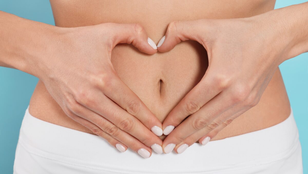 Woman,Making,Heart,With,Hands,On,Her,Belly,Against,Light
