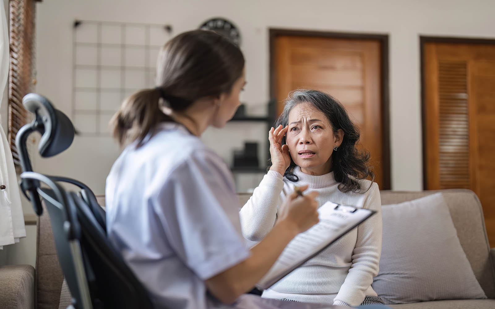Female,Doctor,Is,Examining,Elderly,Patient,While,Taking,Notes,Of