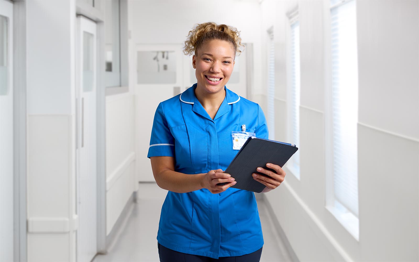 Portrait,Of,Smiling,Female,Nurse,Wearing,Uniform,In,Hospital,Corridor