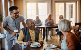 Happy,Senior,People,And,Their,Caregiver,Talking,In,Dining,Room
