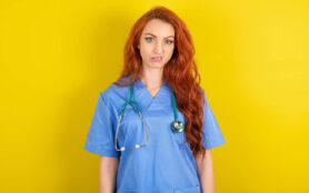 Portrait,Of,Dissatisfied,Young,Red Haired,Doctor,Woman,Over,Yellow,Studio