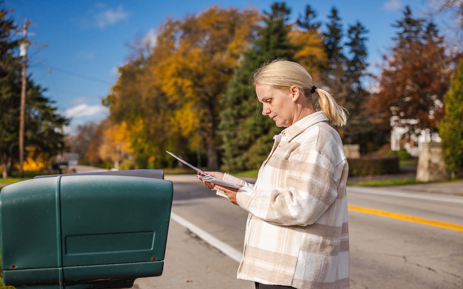 Woman,Standing,Beside,A,Roadside,Mailbox,On,A,Sunny,Autumn